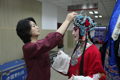 在后台,李胜素团长亲自为即将上场的优秀青年演员朱虹整理头饰